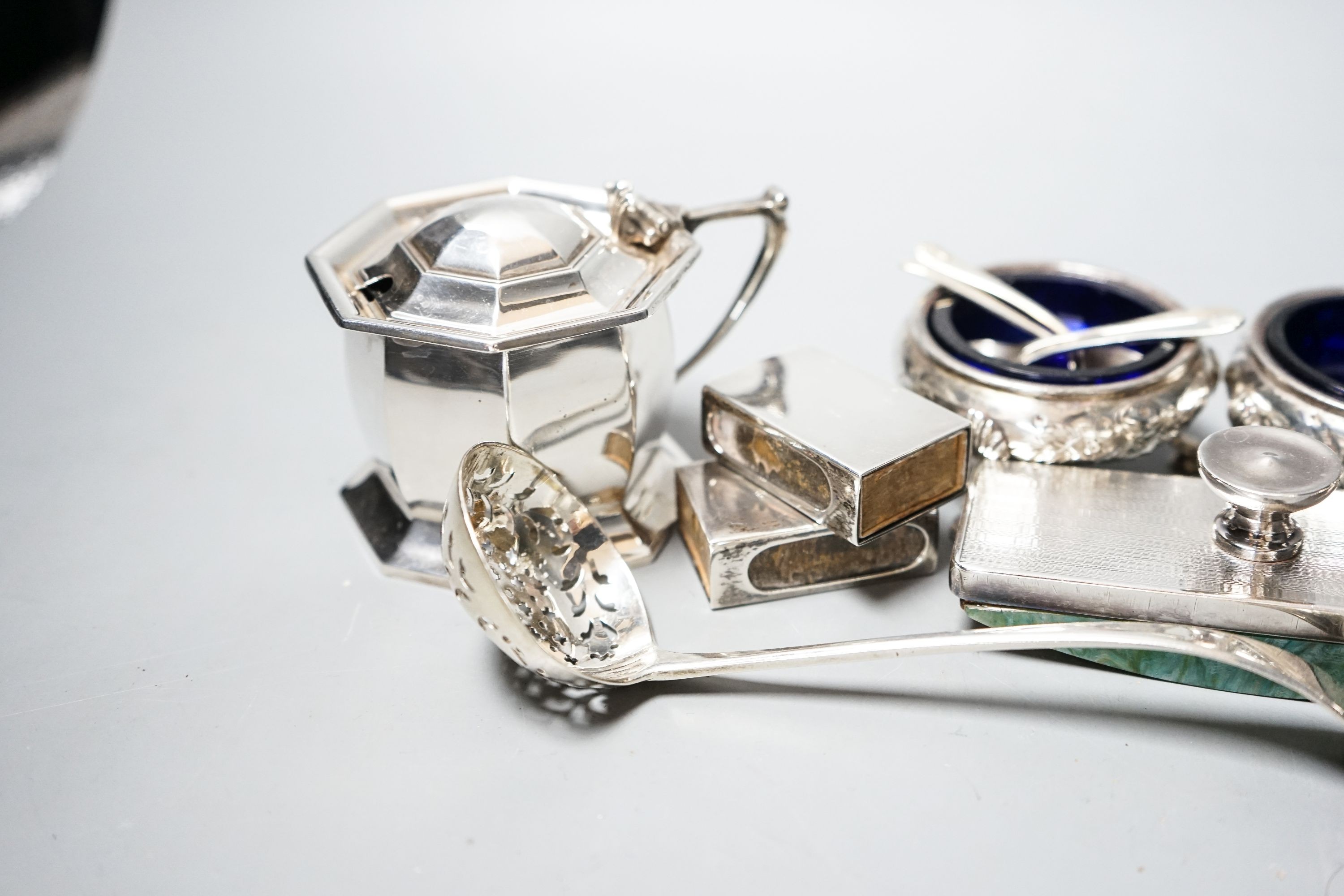 Small silver including a George V silver octagonal mustard, two Victorian bun salts, two shell salts, George III sifter spoon, two condiments, a blotter and two match box sleeves.